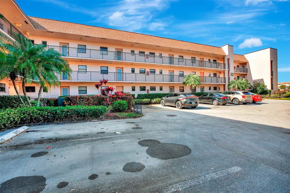 Parking area in front of a multi-story building with balconies.