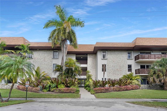 Front view of a three-story building with stone facade and balconies.