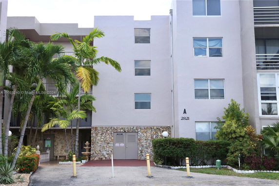 Front view of a multi-story apartment building with stone accents and palm trees.
