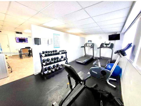 Room equipped with exercise machines and weights for fitness.