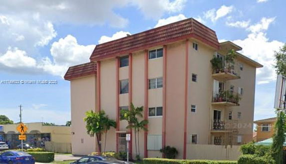 Front view of a multi-story apartment building with a sloped roof.