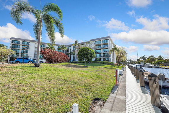 Front view of a multi-story building with balconies and a nearby waterway.