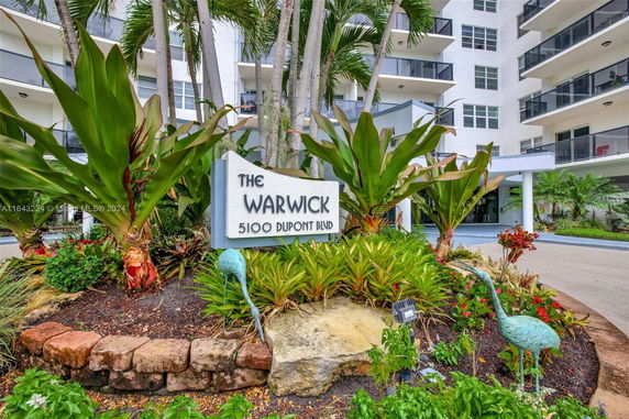 Front view of a multi-story building with a sign and landscaping.