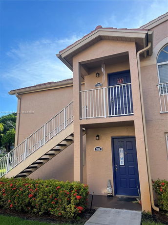 Front view of a two-story building with external staircase and two entry doors.