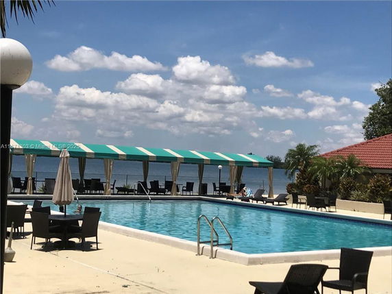 Outdoor swimming pool with seating area and view of a body of water.