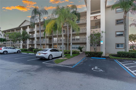 Front view of a multi-story residential building with a parking area.