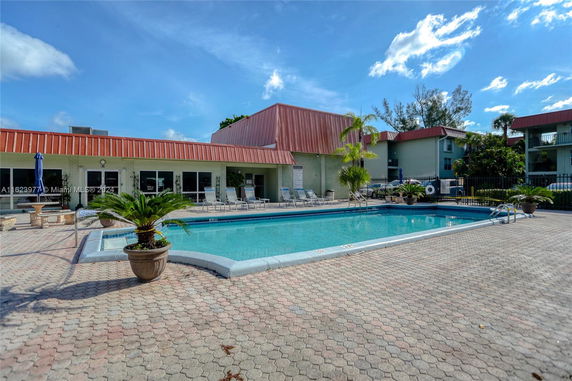Outdoor swimming pool area with lounge chairs and surrounding buildings.