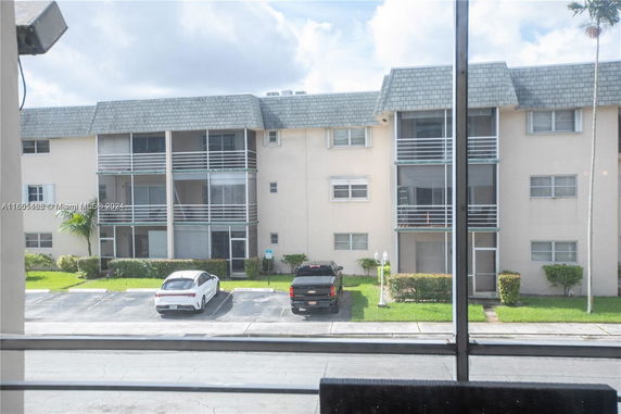 View of an apartment building with balconies and parked cars in front.