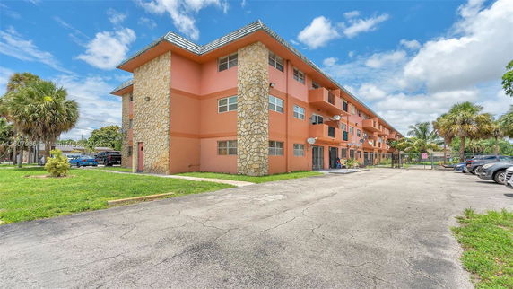 Front view of a three-story apartment building with a parking area.