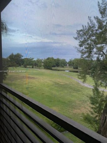 View from a building of a grassy landscape with trees and a walking path.