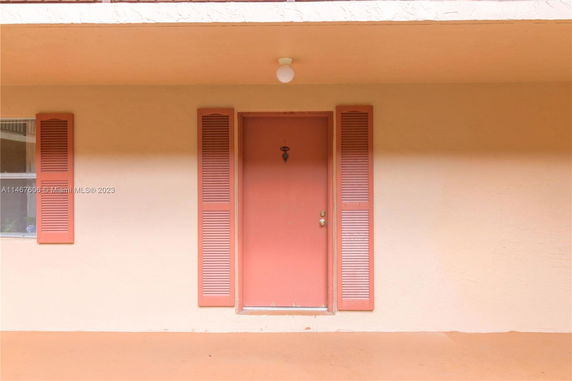 Front view of a building with a single door and shuttered window.