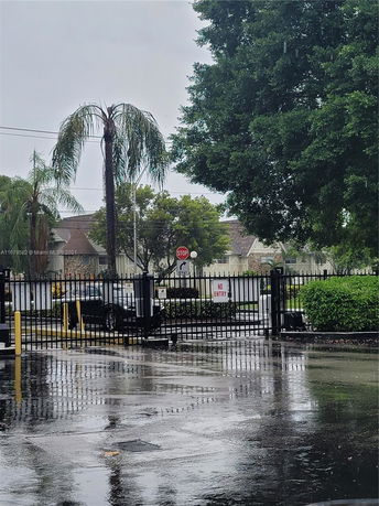 Outdoor parking area with a gated entrance and a wet ground surface.