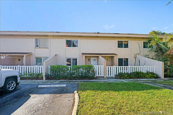 Front view of a two-story residential building with multiple entrances and white fencing.