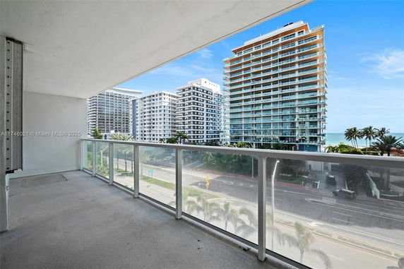 Panoramic view from a balcony showing high-rise buildings and a distant ocean view.