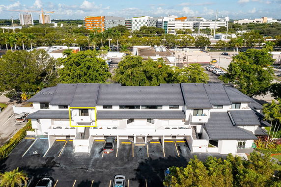 Front view of a multi-story building with a flat roof and covered parking spaces.