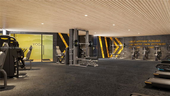 Interior view of a gym with exercise equipment and a glass-walled yoga room.