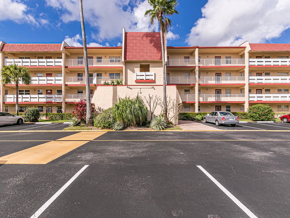 Front view of a multi-story residential building with parking spaces in front.