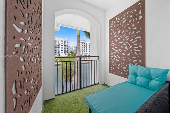 Balcony with decorative panels overlooking a water body and apartment buildings.