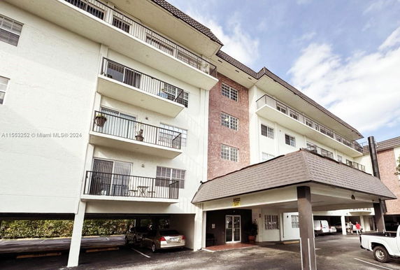 Front view of a multi-story residential building with balconies and a covered entrance.