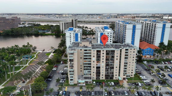 Aerial view of a multi-story apartment building with surrounding parking area.