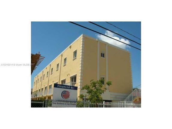 Front view of a three-story yellow building with multiple windows.