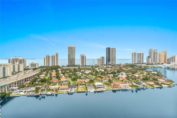 Wide-angle view of a coastal cityscape with high-rise buildings and residential areas by the water.