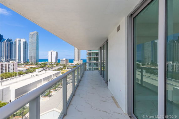 Balcony view from a high-rise building showcasing cityscape with ocean in the background.