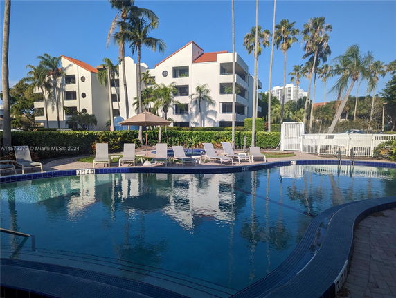 Outdoor swimming pool area with lounge chairs and a modern residential building in the background.