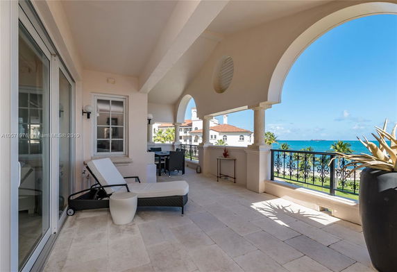 Covered balcony with ocean view and outdoor seating.