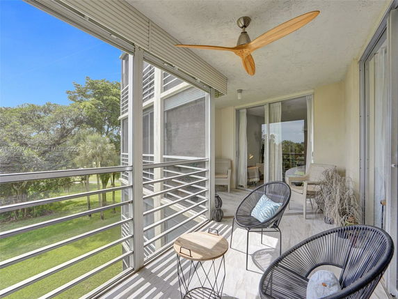Balcony with seating overlooking a grassy area and trees.