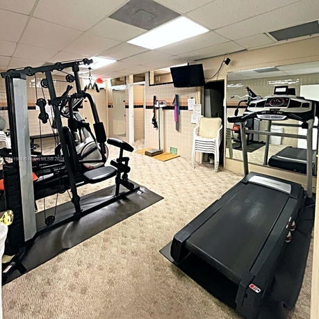 Indoor gym area with exercise equipment including a treadmill and weight machine.