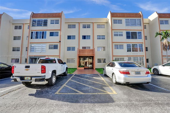 Front view of a multi-story residential building with parking area.