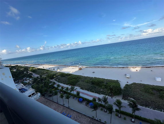 View from a building looking out over a beach and ocean with clear skies.