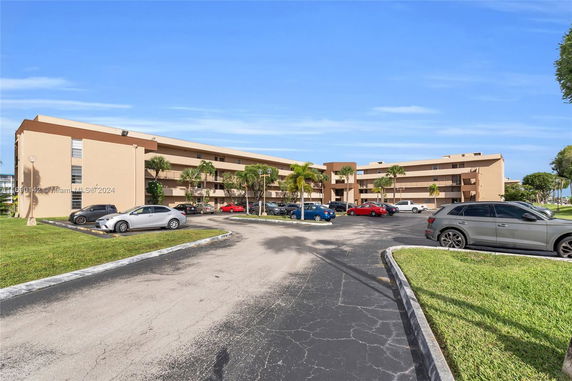 Front view of a multi-story apartment building with parking area.