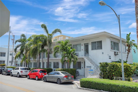 Front view of a two-story residential building with external staircases and palm trees.