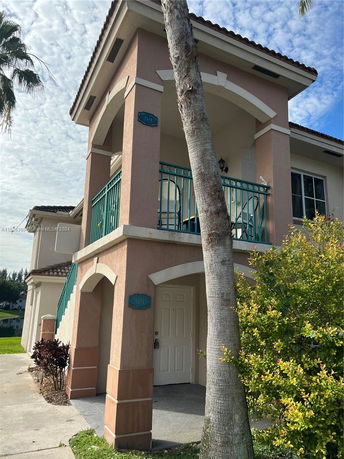 Front view of a two-story house with balconies and arched supports.