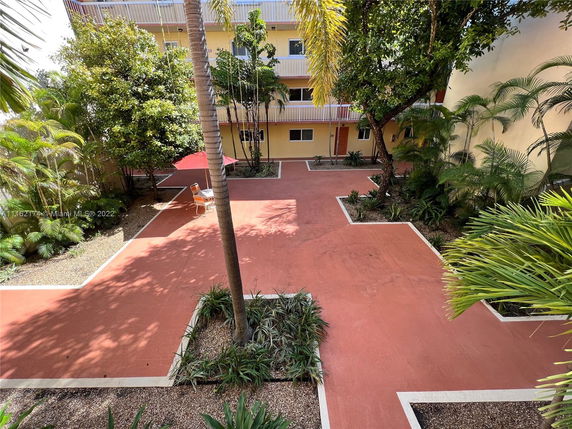 View of a courtyard area with trees and a paved ground.