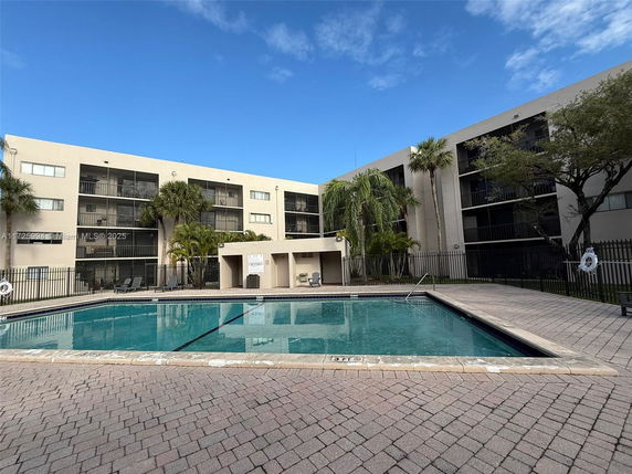 Apartment building with an outdoor swimming pool in front.