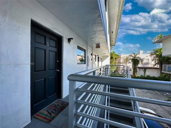 Exterior corridor of a building with railings and view of nearby structures.