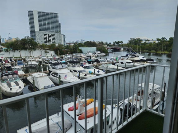 View of a marina with several boats docked and a high-rise building in the background.
