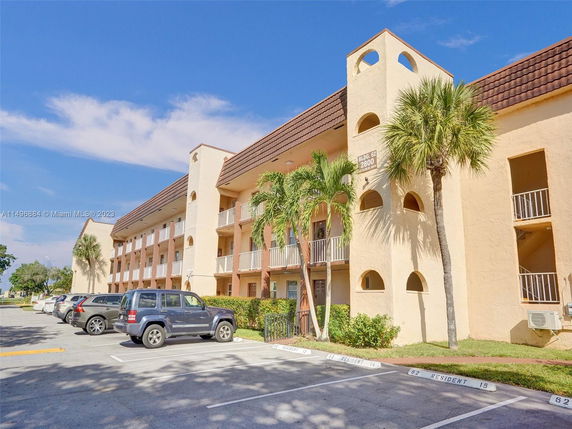 Front view of a multi-story residential building with balconies and parking area.