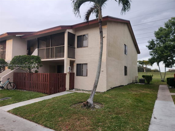 Front view of a two-story house with an exterior staircase and balcony.