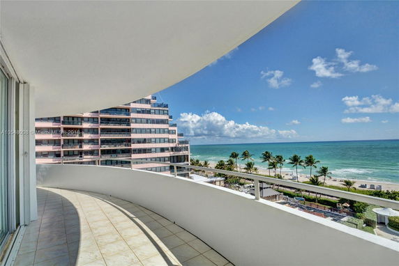 View from a balcony overlooking the ocean and adjacent buildings.