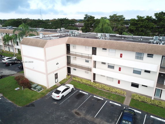 View of a multi-story apartment building with parking area and rooftop units.