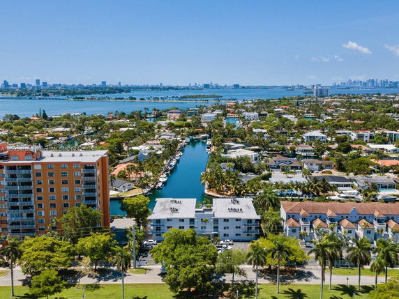 Aerial view of a residential area with waterways and distant city skyline.