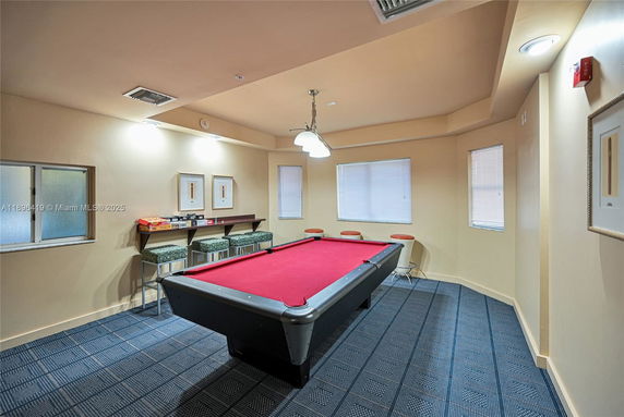 Room with a pool table and bar stools against the wall.