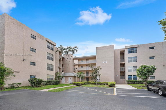 Front view of a multi-story apartment building with a parking area.