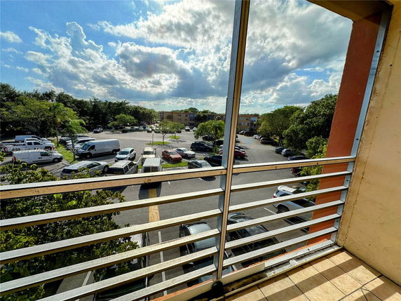 View of a parking area and surrounding greenery from a balcony.
