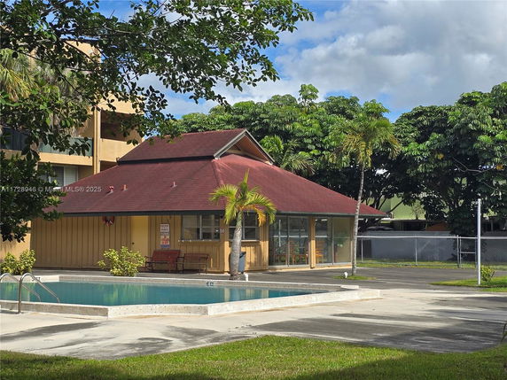 Outdoor view of a house with a swimming pool in front and a red roof.