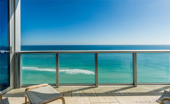 Panoramic view of the ocean from a balcony with glass railing.